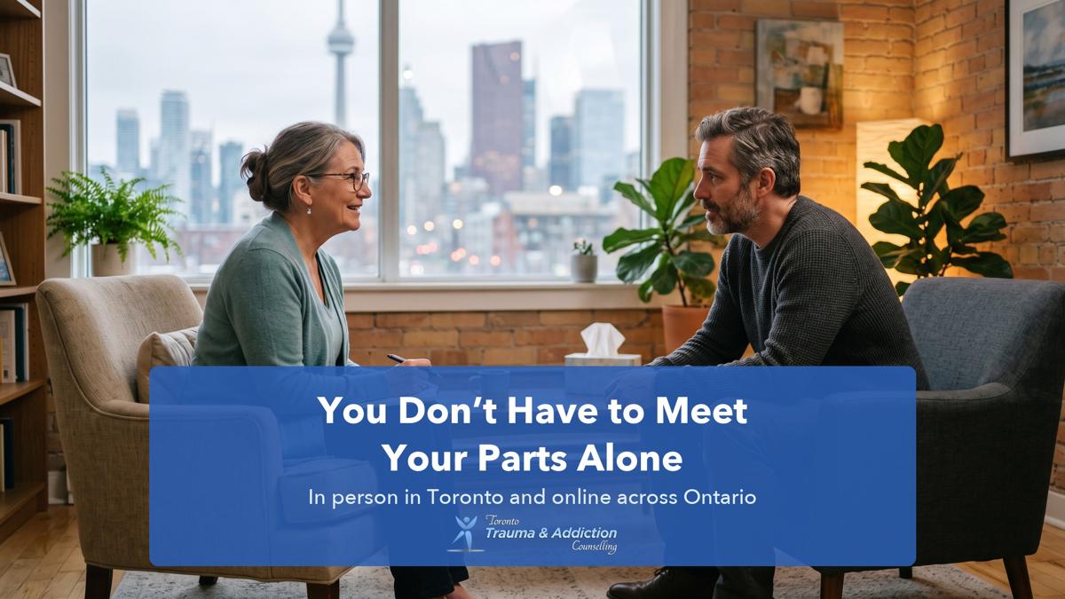 Therapist and client talking in armchairs in a warm Toronto counselling office, with the CN Tower visible through the window.