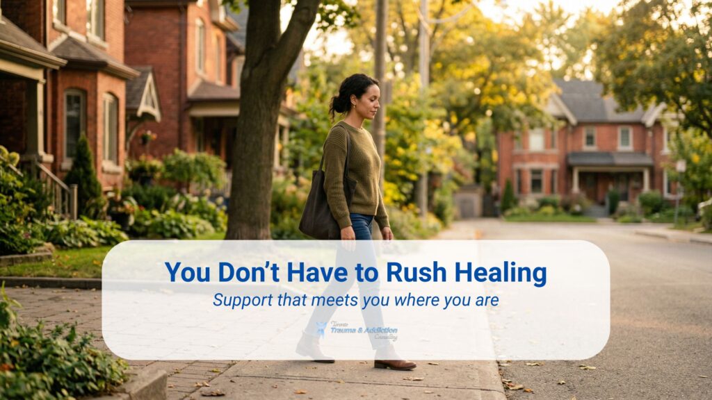 Woman walking alone on a quiet residential Toronto street surrounded by trees and homes, representing a slow and personal trauma healing journey with supportive counselling