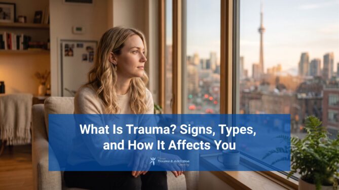 Woman sitting indoors by a window looking out at the Toronto skyline with CN Tower, reflecting on trauma, mental health, and emotional wellbeing in a calm home setting